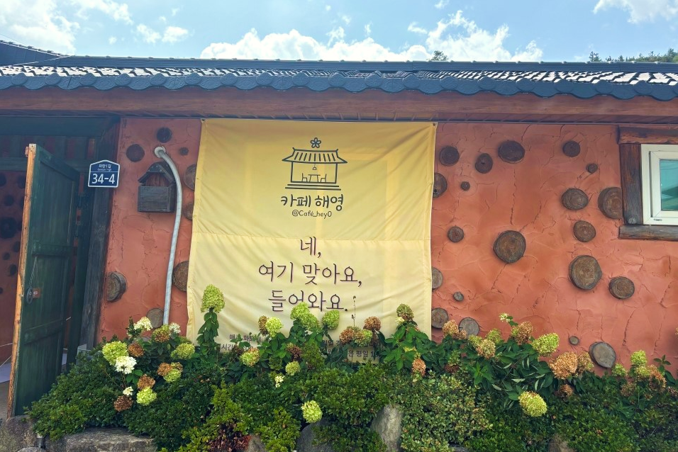 카페 해영 흙집 벽과 안내 현수막